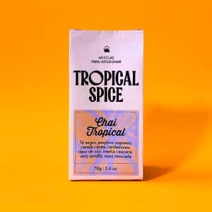 Empaque biodegradable del chai tropical de Tropical Spice, mezcla en polvo con té negro, jengibre, copoazú, canela cassia, cardamomo, clavo, menta, anís y nuez moscada. Fondo naranja brillante.