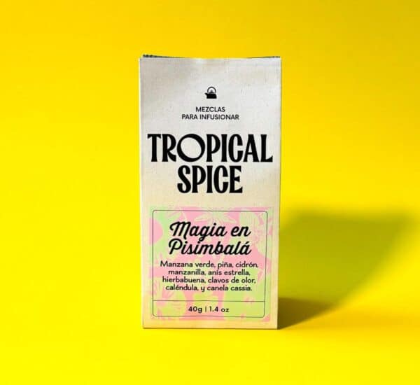 Empaque biodegradable de la mezcla de infusión Magia en Pisimbalá de Tropical Spice, que combina manzana, piña, cidrón, manzanilla, hierbabuena, anís estrella, clavos, caléndula y canela. Fondo amarillo claro.