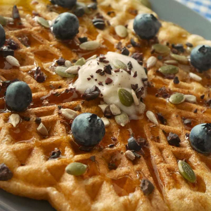Waffle con arándanos frescos, crema vegetal y semillas tostadas, preparado con toques de especias Tropical Spice.