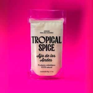 Ajo de los Andes en polvo de Tropical Spice, empacado en bolsa transparente sobre fondo fucsia degradado.