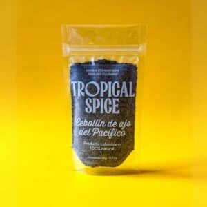 Cebollín de ajo del Pacífico triturado de Tropical Spice, empacado en bolsa doypack transparente sobre fondo amarillo degradado.