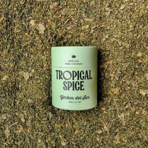 Envase biodegradable de Yerbas del Sur de Tropical Spice sobre fondo de mezcla de hierbas deshidratadas.