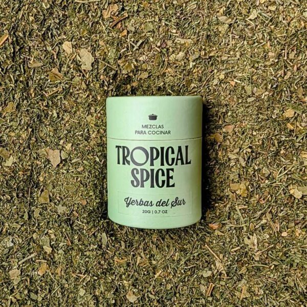 Envase biodegradable de Yerbas del Sur de Tropical Spice sobre fondo de mezcla de hierbas deshidratadas.