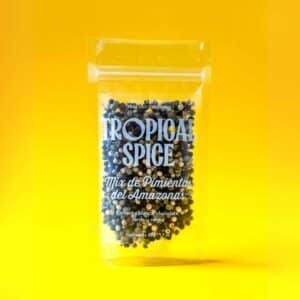 Mix de pimientas en grano del Amazonas de Tropical Spice, empacado en bolsa transparente doypack sobre fondo naranja-amarillo