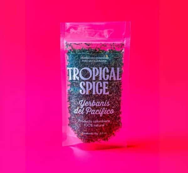 Yerbanís triturado del Pacífico colombiano de Tropical Spice, empacado en bolsa transparente doypack sobre fondo fucsia