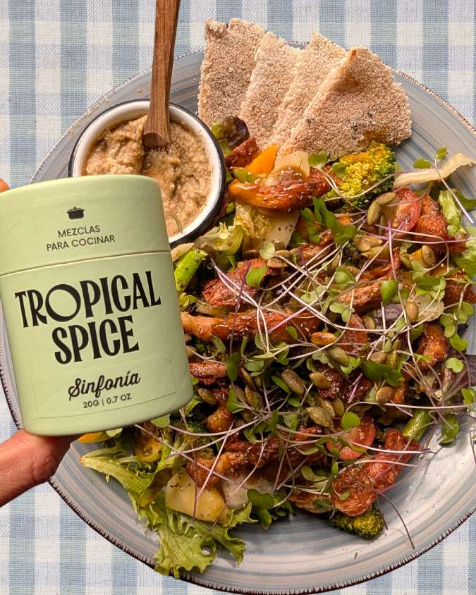 Ensalada tropical con hongos, mango, semillas y mezcla Sinfonía de Tropical Spice al frente, acompañada de casabe y hummus.