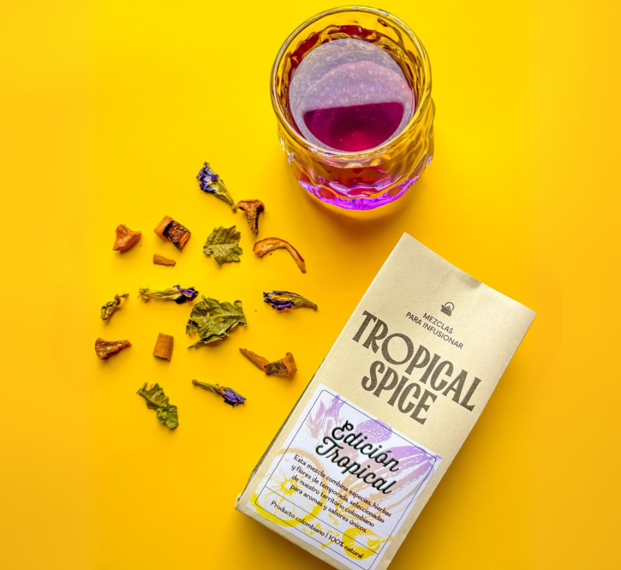 Mezcla de flores, hierbas y especias naturales de la Edición Tropical de Tropical Spice lista para infusionar, con infusión morada sobre fondo amarillo.